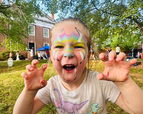 A child in rainbow face paint growls for the camera.