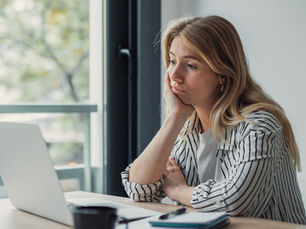 Ondernemer kijkt bezorgd naar haar laptop en notitieblok, worstelend met het verschil tussen winst en cashflow in haar bedrijf