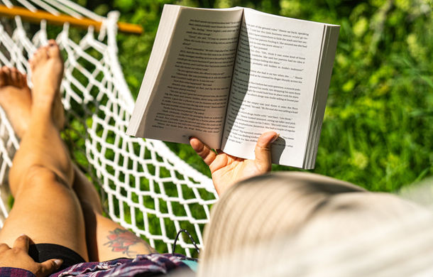 A woman is reading a book while gently swinging in a hammock at Boho Beaver.