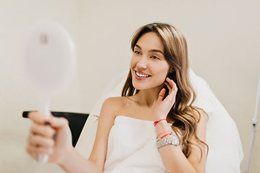 happy-beautiful-woman-with-long-brunette-hair-after-cosmetology-therapy-smiling-mirror-whi