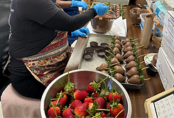 Staff member at Purity Candy dipping strawberries into chocolate