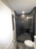 Modern bathroom with glass walk-in shower and grey tile.