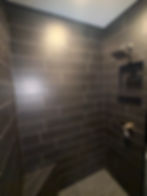 Modern bathroom shower with dark wood-look tile and niche.