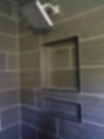 Modern bathroom shower with gray tile and built-in niches.