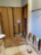 Bathroom under construction with exposed wall studs and plumbing.