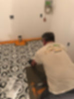 Worker installing patterned flooring tile in a room.