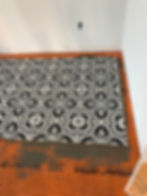 Black and white patterned flooring tiles being installed.