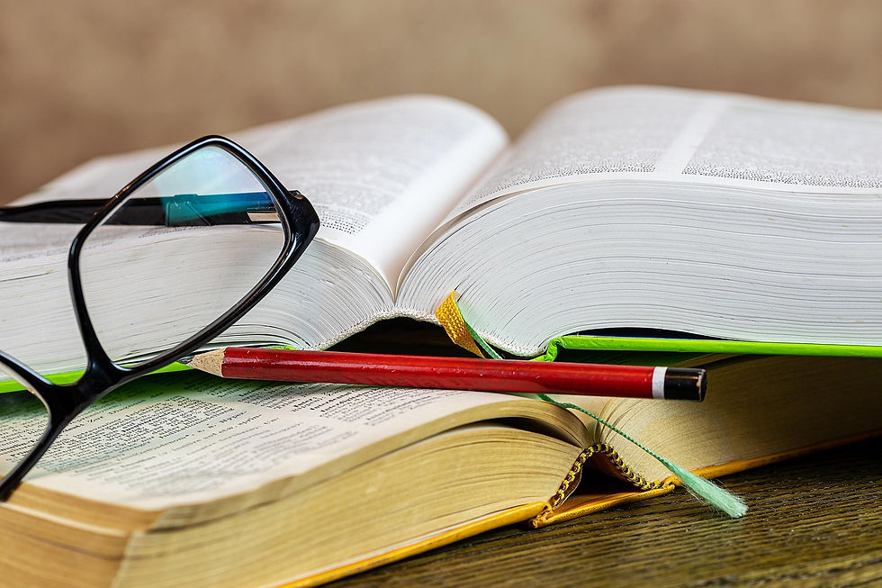 Open books with a red pencil and black glasses on top. Pages show text, creating a studious vibe. Background is a soft, neutral tone.