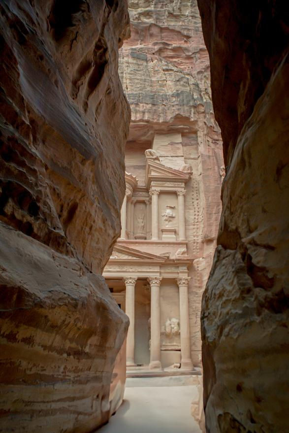 Ancient rock-carved facade of Petra's Treasury framed by narrow canyon walls, with earthy tones and an air of mystery.