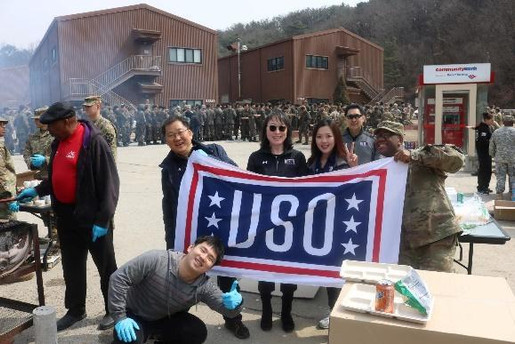 USO volunteers holding USO flag while serving military servicemembers