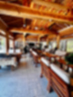 Wooden interior with tables and chairs in bright cafe. Guitars on walls; large windows illuminate space. Warm, cozy, rustic ambiance.