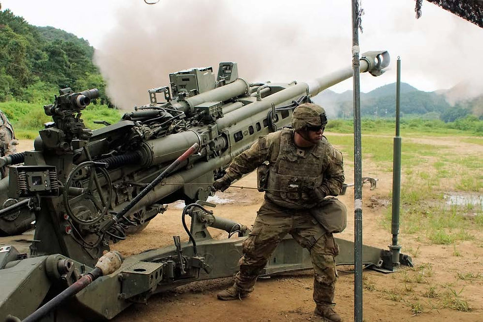 Soldier in camo operates artillery in a grassy field with mountains. Smoke billows from the cannon, creating a tense atmosphere.