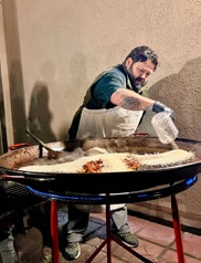 chef pouring rice into paella