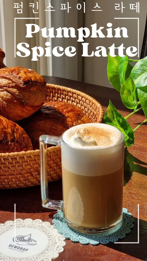 A pumpkin spice latte in a glass mug on a table with pastries and a plant. Text reads "Pumpkin Spice Latte." Light, cozy atmosphere.