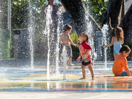 four children playing in a splash pad in the summer