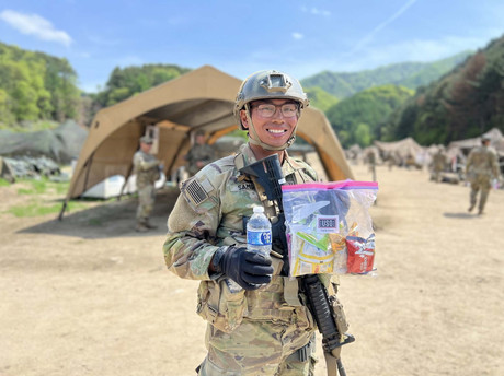 soldier smiling and holding food and water given by USO
