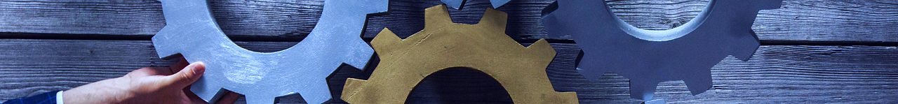 Group of business people joining together silver and golden colored gears on table at work