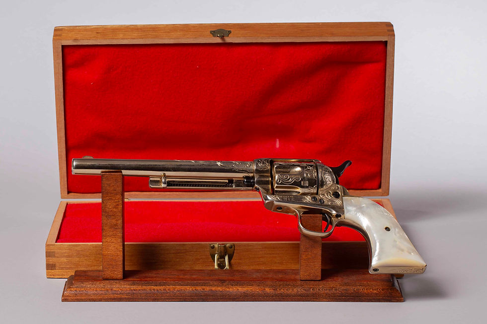 Full left-side view of Colt Single Action Army revolver with nickel finish, pearl grips, and factory engraving, displayed in