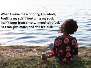 A woman sitting down opposite a river, reflecting and tending to her self care