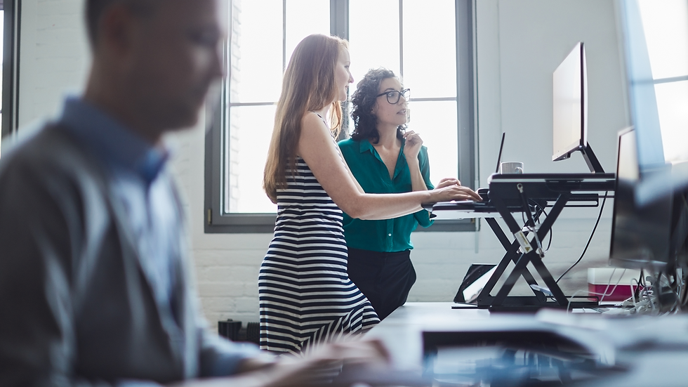 Two female corporate employees at a standing desk in an office environment