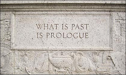 Stone wall engraved with "WHAT IS PAST IS PROLOGUE" in all caps, surrounded by intricate carvings. Text-centric and historical in tone.