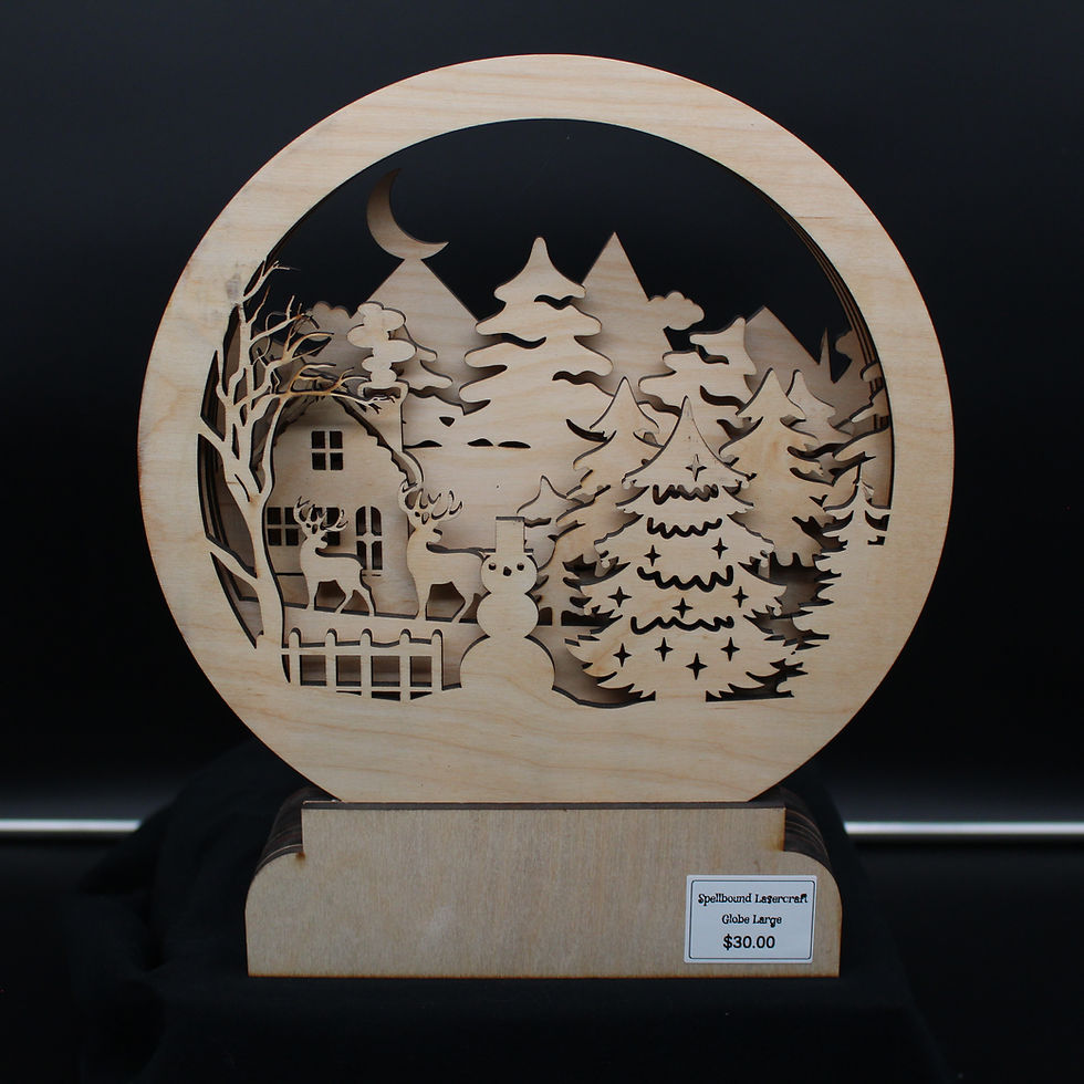 Wooden laser-cut Christmas scene with trees, house, moon, and visible text. SpellBound LaserCraft LLC