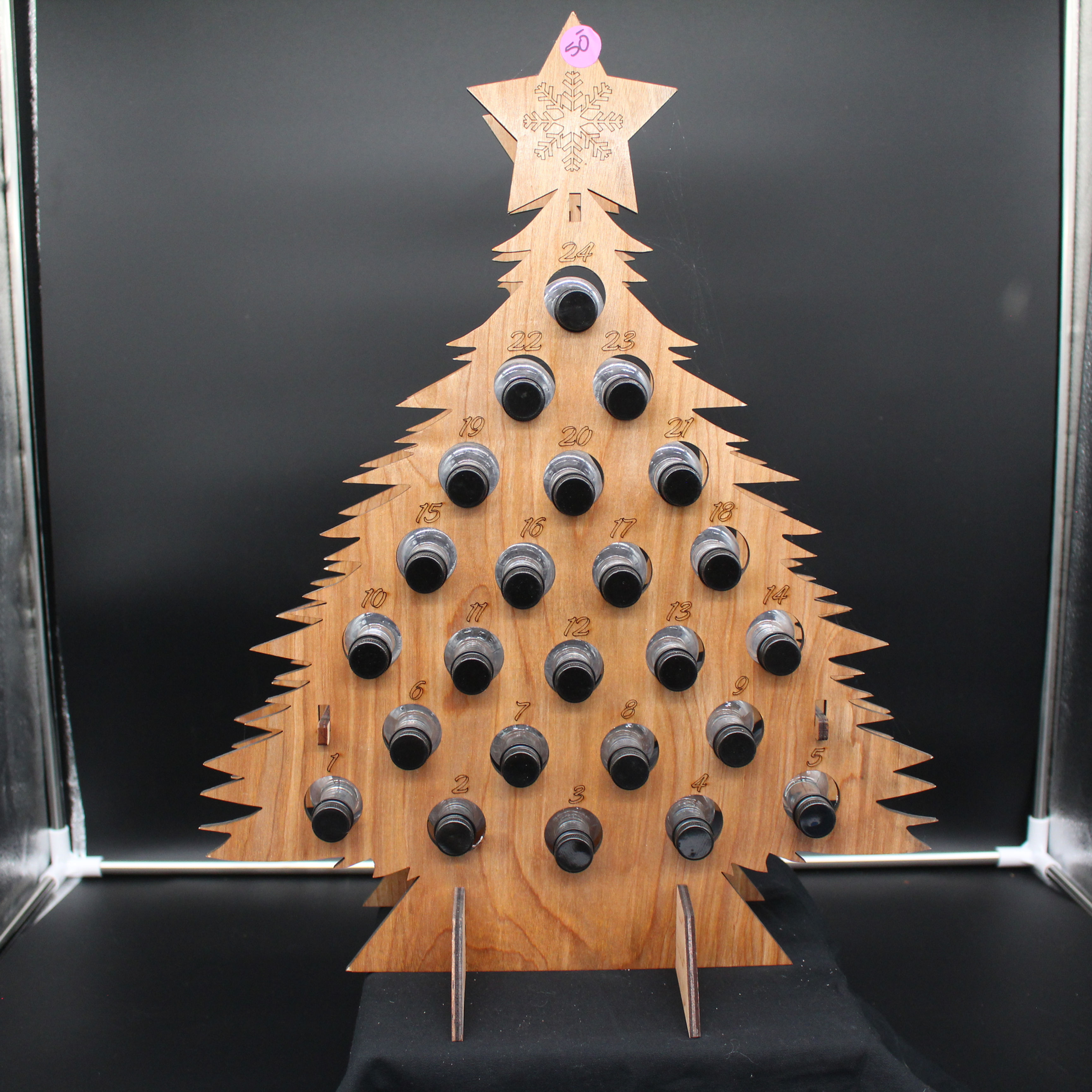 Wooden Christmas tree with bells and star shaped top decoration, black background.
