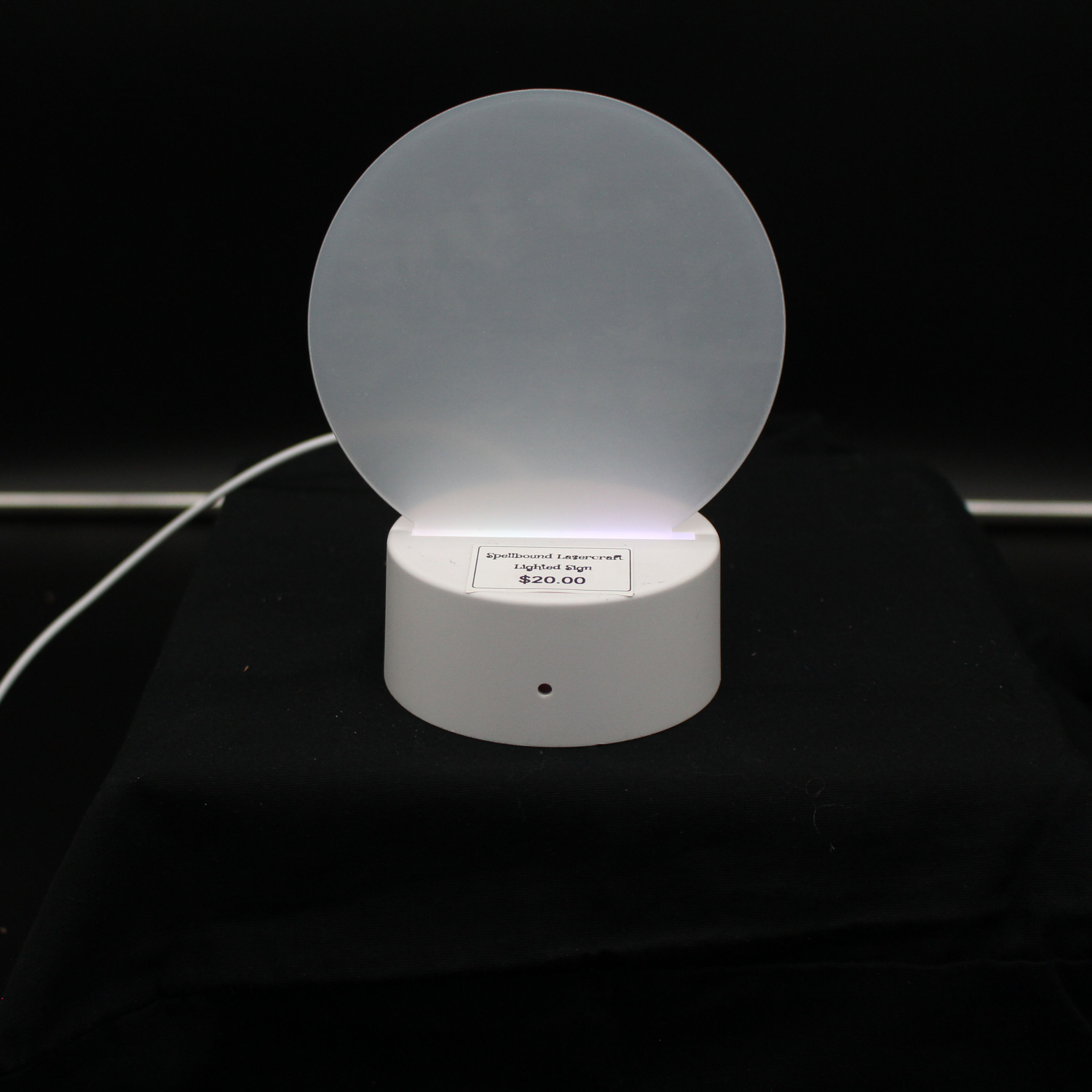 White circular LED lamp with a glowing light on a black background