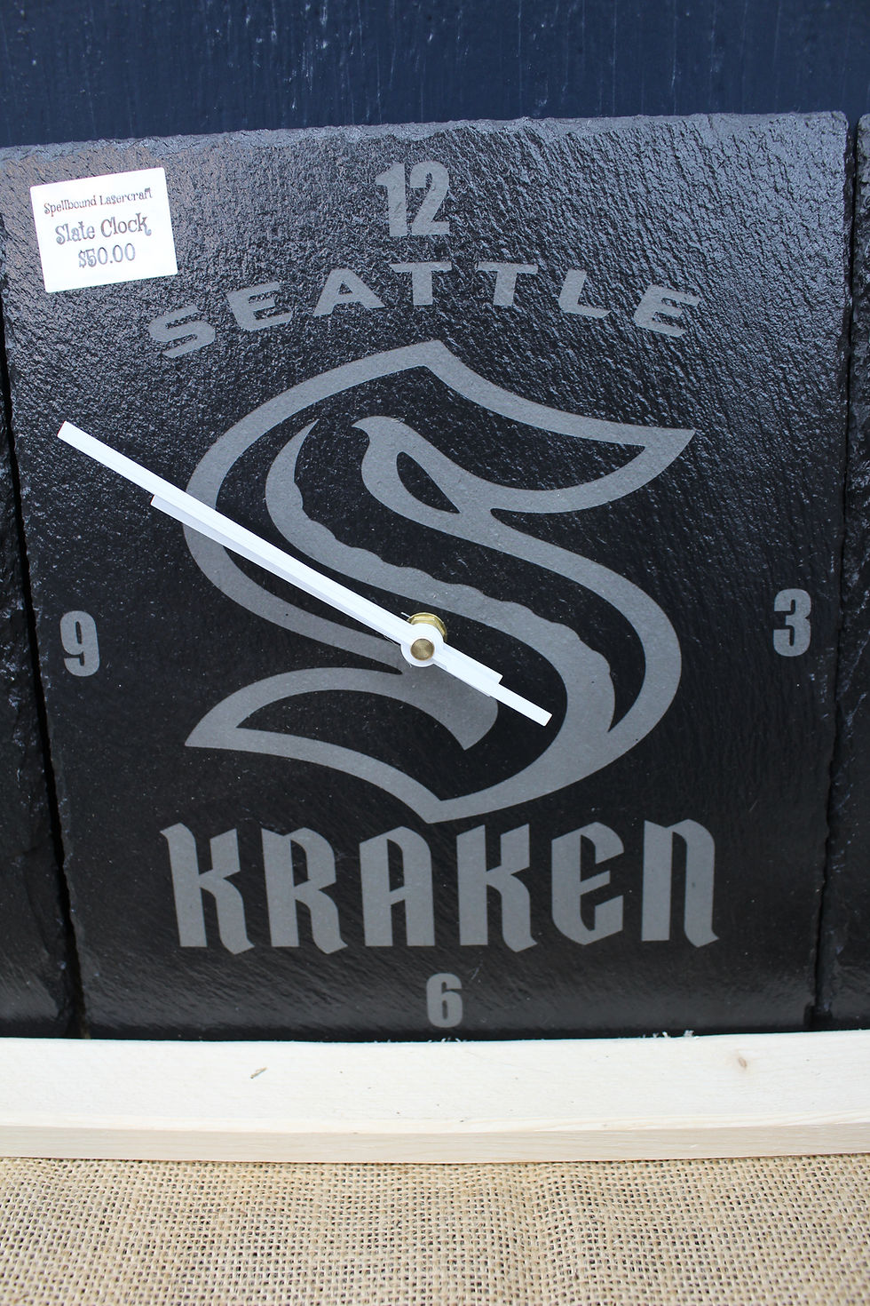 Seattle Kraken clock with logo and numbers on black background.