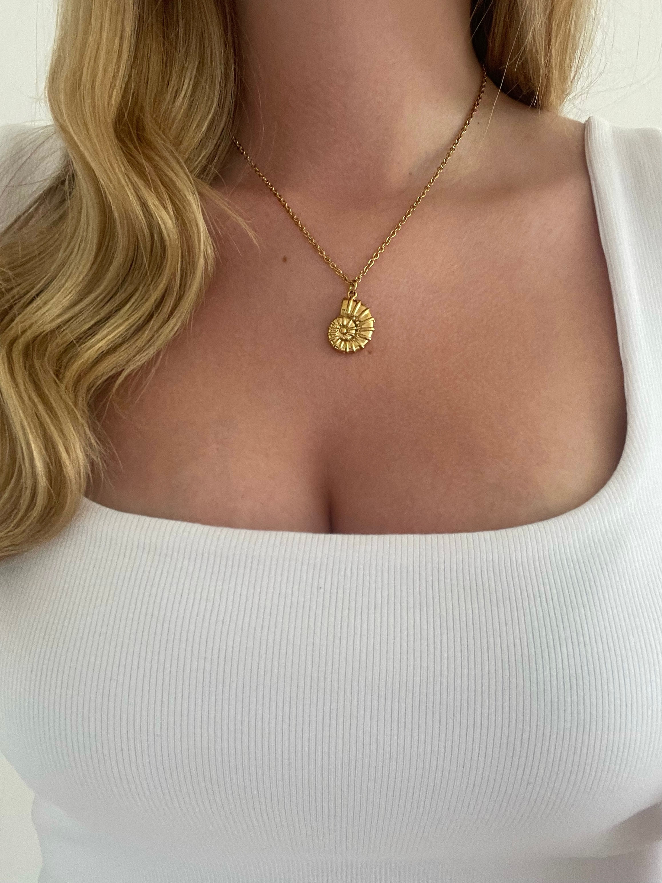 Gold spiral shell pendant necklace on model