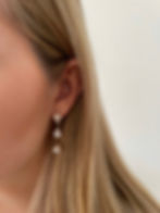 Close up of a model wearing Amoria gold triple drop earrings with pear-cut cubic zirconia for a bridal look.