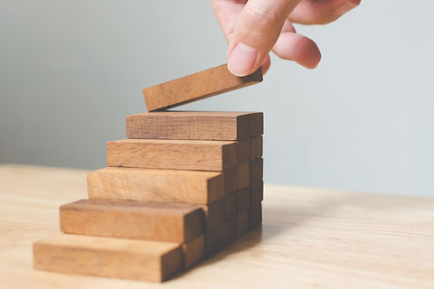 Hand arranging wood block stacking as step stair. Ladder career path concept for business