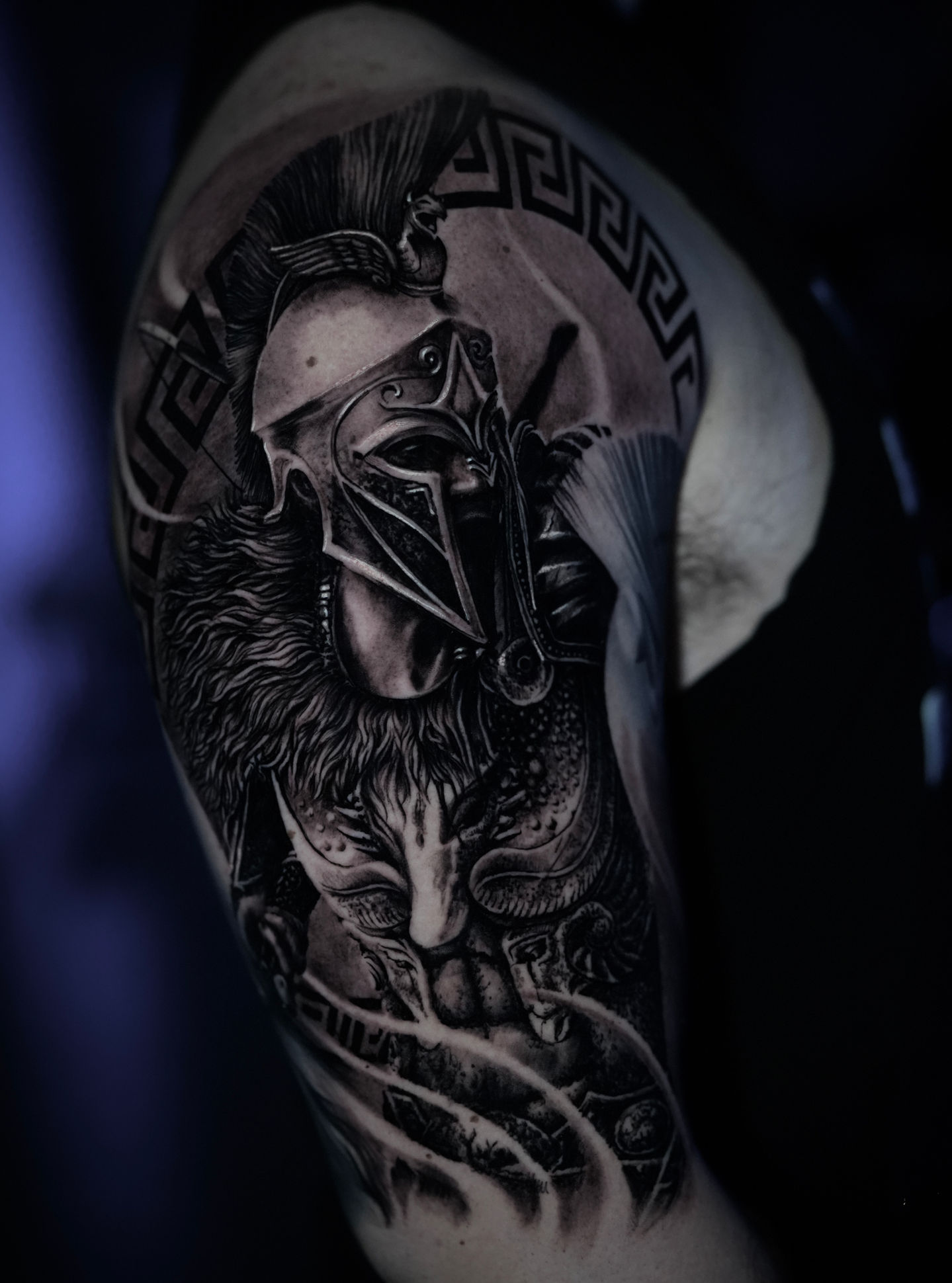 Close-up of a black and gray tattoo depicting a Spartan warrior in detailed armor with a helmet and fur cape