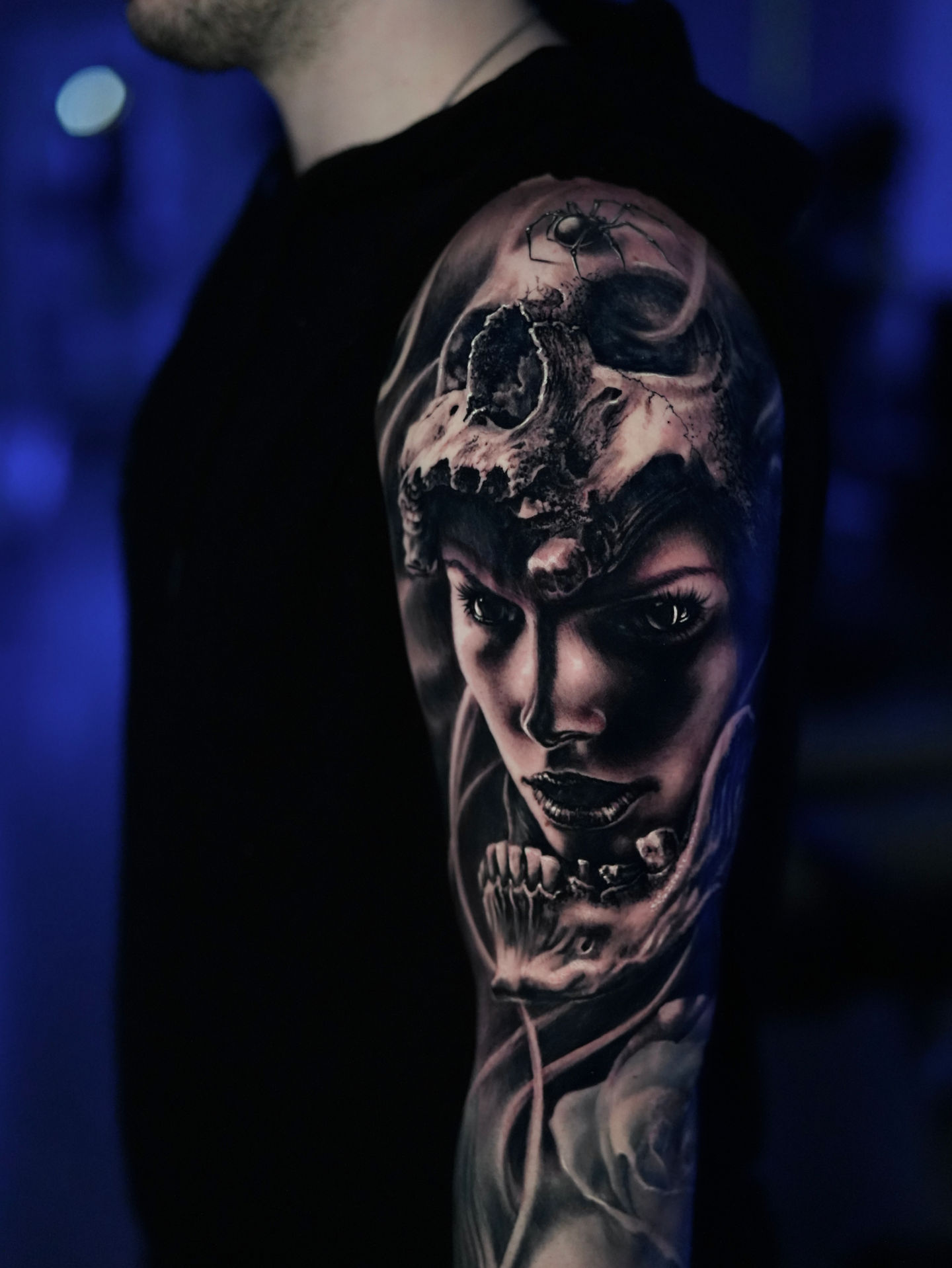 Close-up of a vibrant tattoo featuring a woman’s face adorned with a skull headdress, combining realism and surreal elements