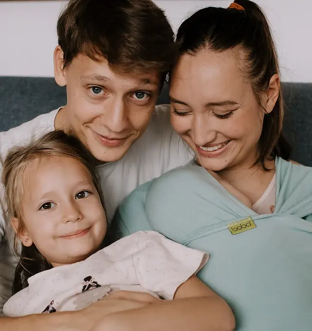 Family photo with a mommy wearing their baby in a Boba Bliss baby carrier, with a father and older sister