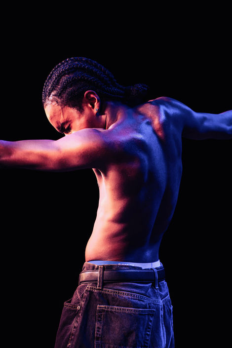 Shirtless rapper BabyChiefDoIt posing under dramatic blue and orange lighting on RAMBO Tour in Denver.