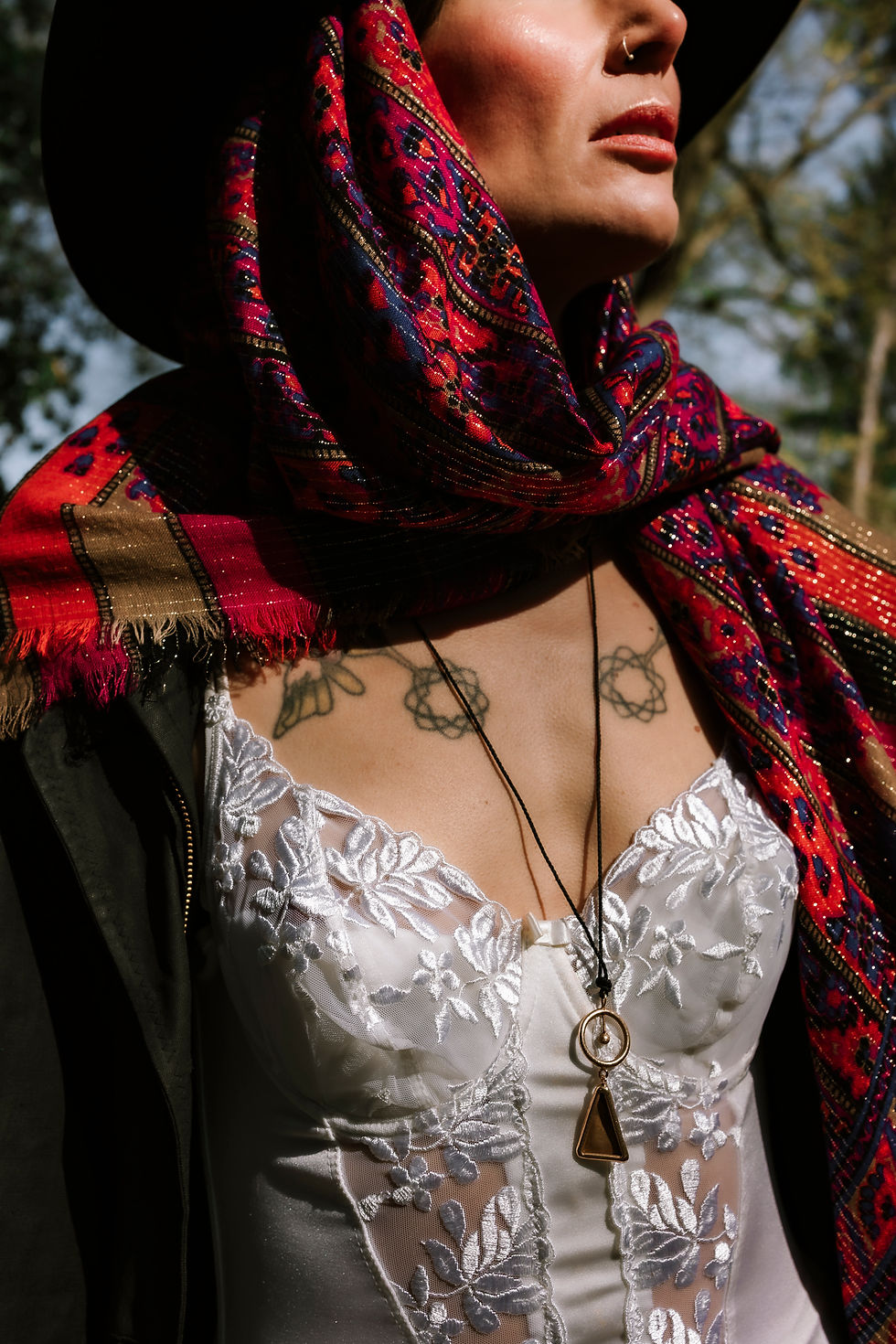 Dettaglio di persona con sciarpa colorata e collana con ciondolo.