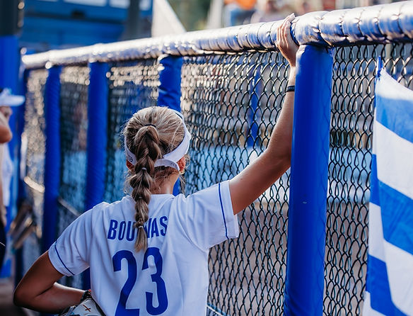 Young woman with braid wearing BOUZAS 23 jersey leans on fence