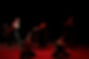 Group of dancers performing contemporary dance on stage with red lighting