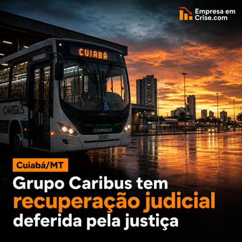 Ônibus urbano moderno do Grupo Caribus estacionado em terminal de transporte coletivo, em Cuiabá/MT, sob céu dramático ao entardecer, com prédios e iluminação urbana ao fundo e reflexos no pavimento molhado. Sobre a imagem, o texto informa: “Cuiabá/MT – Grupo Caribus tem recuperação judicial deferida pela justiça”, com destaque em laranja para “recuperação judicial” e a logo Empresa em Crise.com no canto superior direito.