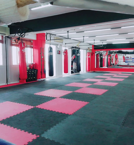The inside of a boxing gym, with punching bags on the left side and a mirror