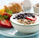 healthy breakfast array with bowl of oats and berries, strawberries, water, and croissant