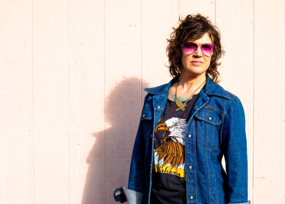 Sara Thompson in denim jacket and red shades 