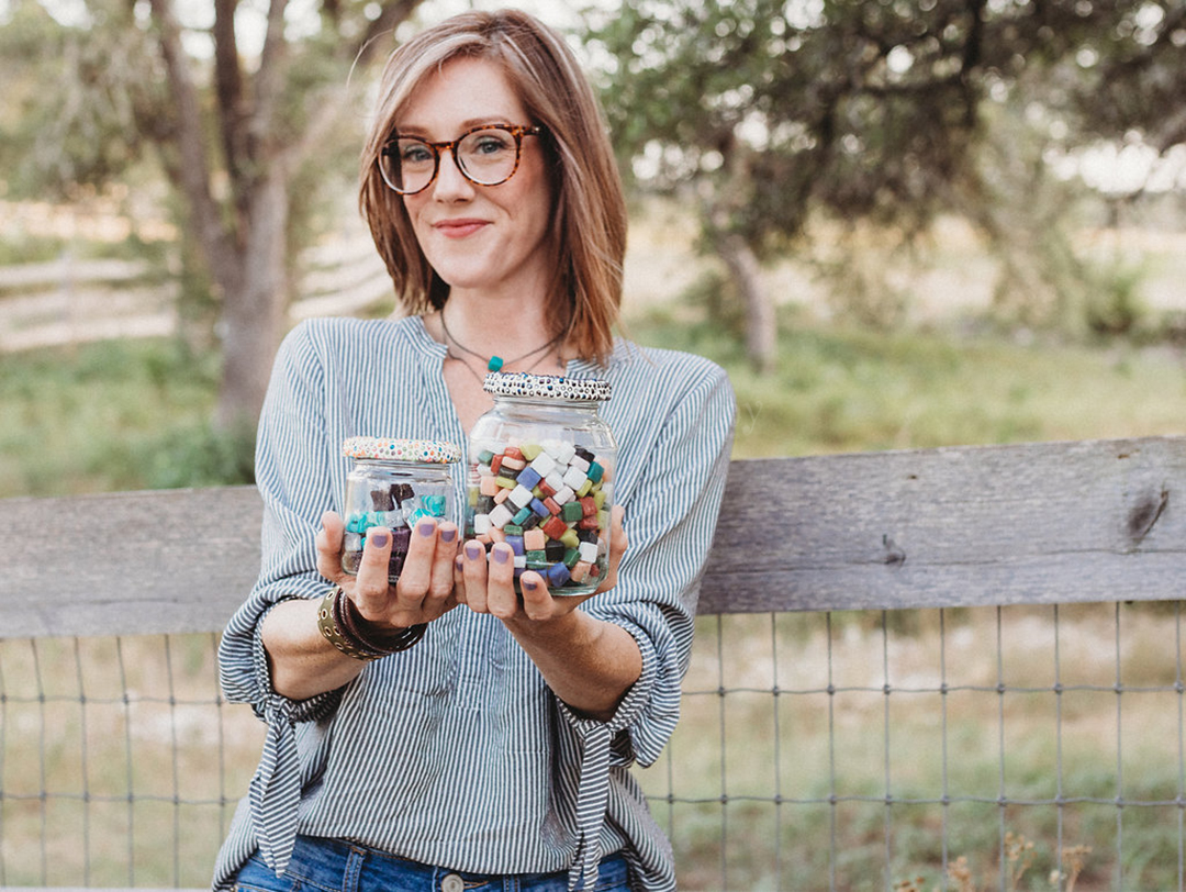 Amy Jones outside with a jar and bag of colorful beads