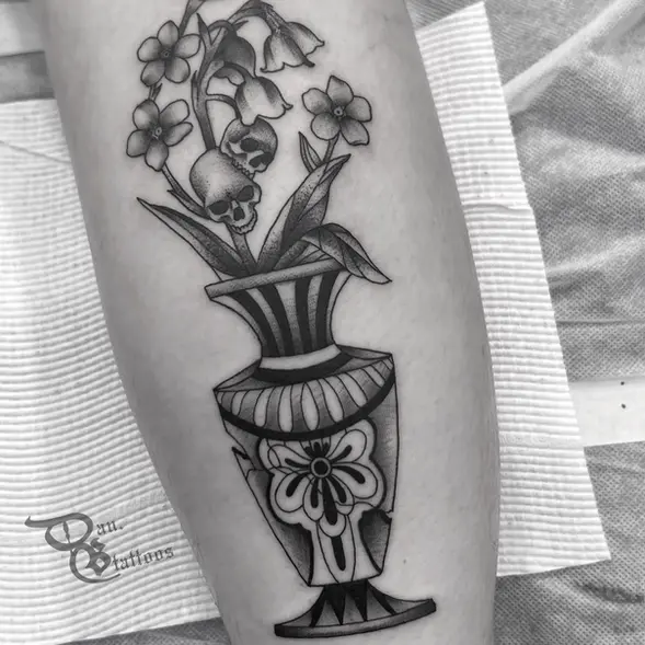 Traditional black and grey tattoo with a cracked vase, flowers and skulls