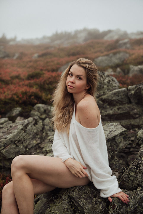 Boudoir kuvassa Levitunturilla vaaleatukkainen nainen istuu pirunpellon kivellä toinen jalka koukussa. Koukussa olevan jalan puoleinen käsi on kivellä jalan vieressä. Naisella on yllään valkoinen, kevyt ja iso neulepaita. Neule on laskettu hartialta ja naisen vasen olkapää näkyy. Nainen katsoo suoraan kameraan vakavalla ilmeellä. Naisen hiukset ovat kasvojen oikealla puolella. Naisen pää on hieman takakenossa ja naisen jalat ovat paljaat.
