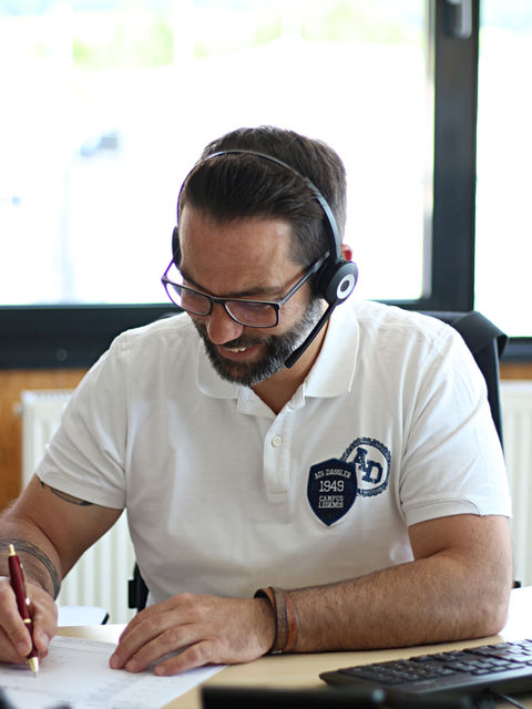 ein Mann mit Headset schreibt etwas auf ein Blatt