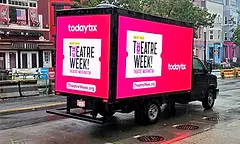 A TodayTix "Theatre Week" campaign glowed from two pink screens on a rain-slicked Washington DC street at dusk, run through MATV Mobile Billboard Advertising. The campaign used Stationary Advertising and Guerrilla Advertising across Shows & Conventions and Ticket Sales goals to promote the citywide celebration and drive theatre ticket sales.