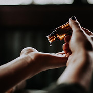 a woman holding her hand out while dripping skin oil on her hand