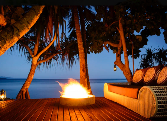Beachfront fire pit on a wooden deck at night in Fiji.